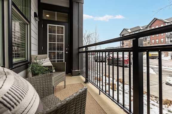 A black metal railing on a balcony with a chair and a potted plant.