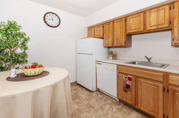 A kitchen with a white fridge and wooden cabinets. at North Pointe Apartments, Clifton Park, NY, 12065