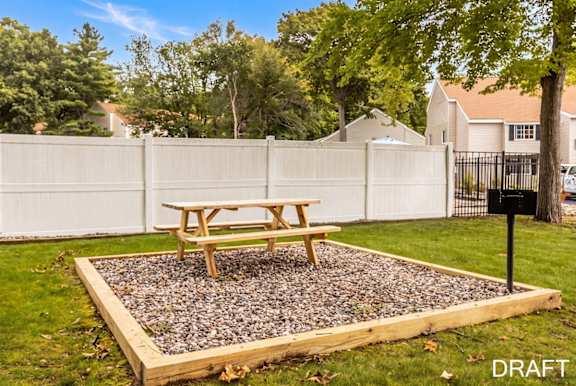 A picnic table sits in a gravel pit in a backyard.
