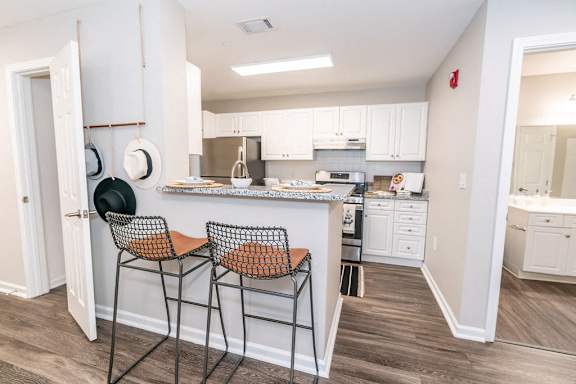 a kitchen with white cabinets and a counter top with two stools