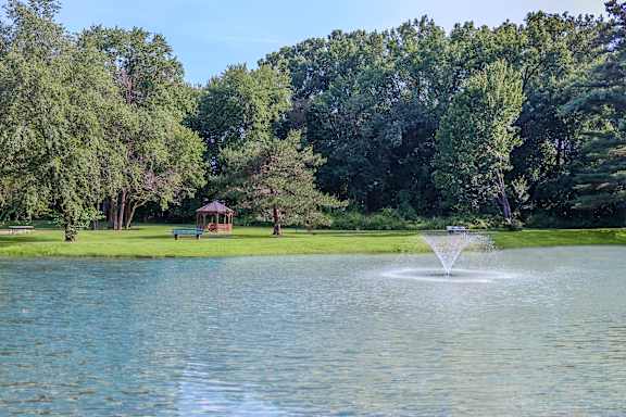 A fountain in the middle of a lake surrounded by trees.