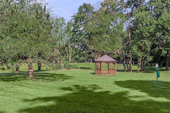 A gazebo sits in the middle of a grassy field.
