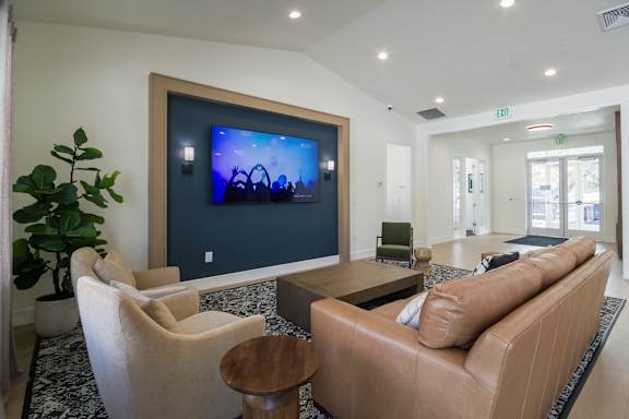 A living room with a large screen television and comfortable seating.
