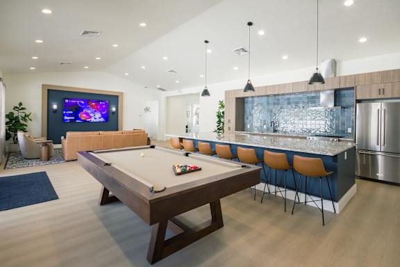 A pool table in a room with a TV and a bar.