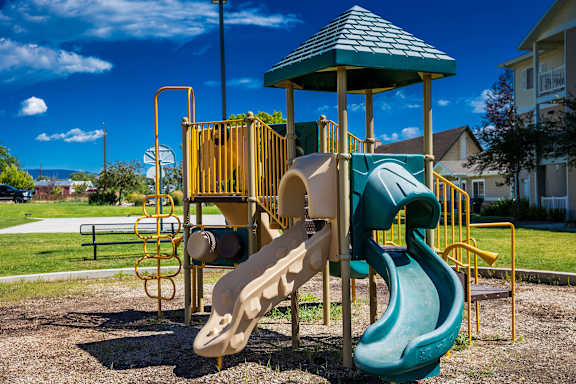 A playground with a green slide and a yellow structure.