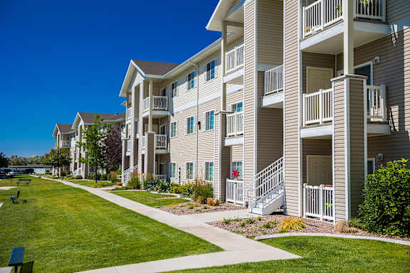 A row of apartment buildings with balconies and flower pots on the steps.