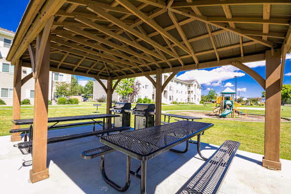 A wooden pavilion with a black table and benches.