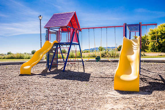 A playground with a yellow slide and a red and blue structure.