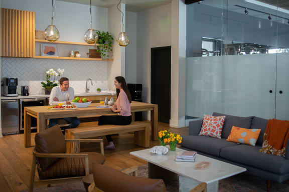 A man and a woman sitting at a wooden table in a living room at Mariposa on 3rd, Los Angeles, CA 90004