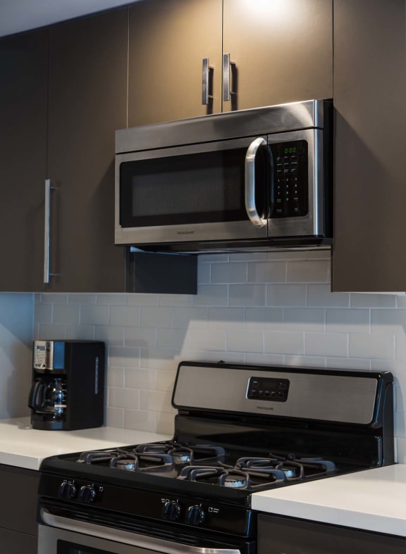 Kitchen with a stove top oven next to a microwave at 888 Hilgard – Furnished Apartments, Los Angeles