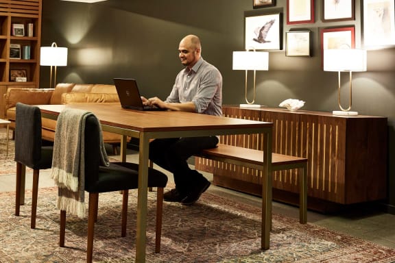 Man sitting at a table using a laptop computer at 888 Hilgard – Furnished Apartments, Los Angeles
