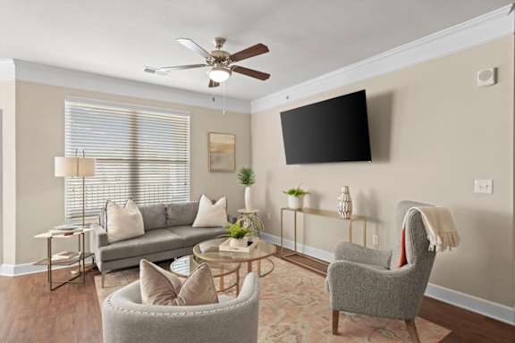 A living room with a grey couch, a grey armchair, a coffee table, and a ceiling fan.