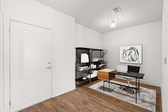 A room with a desk, laptop, and bookshelf.
