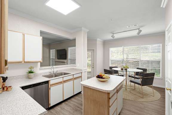 A large kitchen with white oak cabinets, stainless steel appliances, track lighting and a kitchen island.