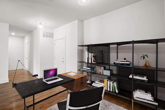 A black desk with a laptop on it in a room.