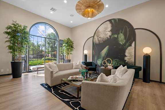 A living room with a large window and a painting on the wall.