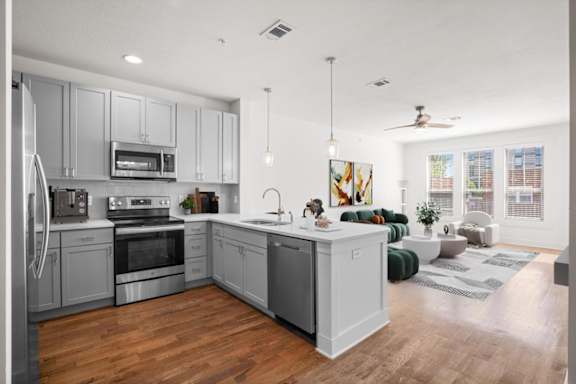 a kitchen with a large center island next to a living room with a couch and a window at Mirabelle Luxury Apartments, Kansas City, MO 64111