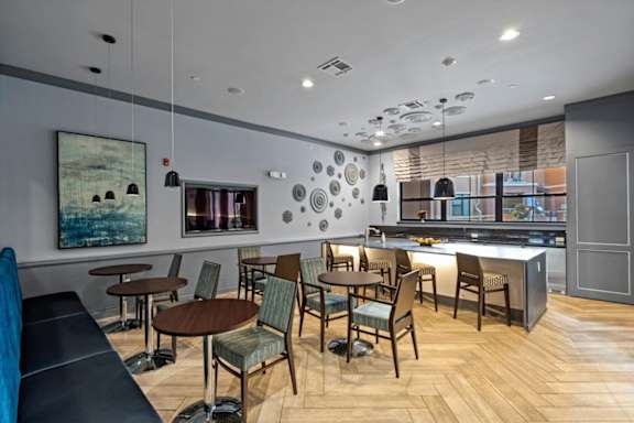 A modern dining area with wooden floors and a mix of chairs and tables.