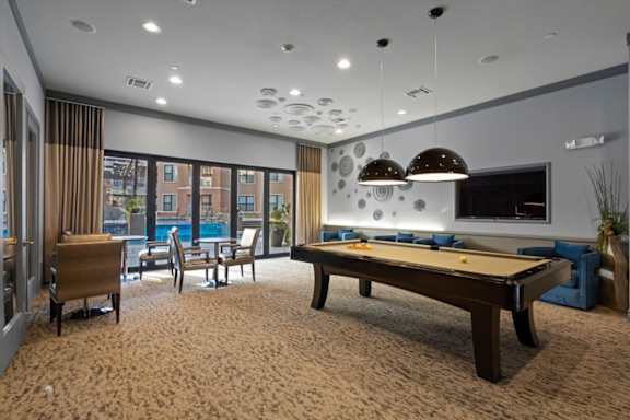 A room with a pool table and a view of a building outside the window.