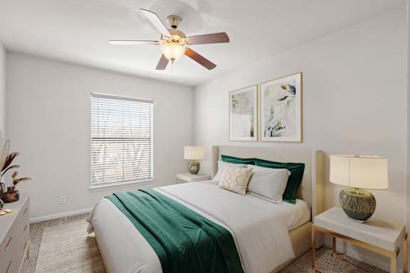 A bedroom with a ceiling fan and window.