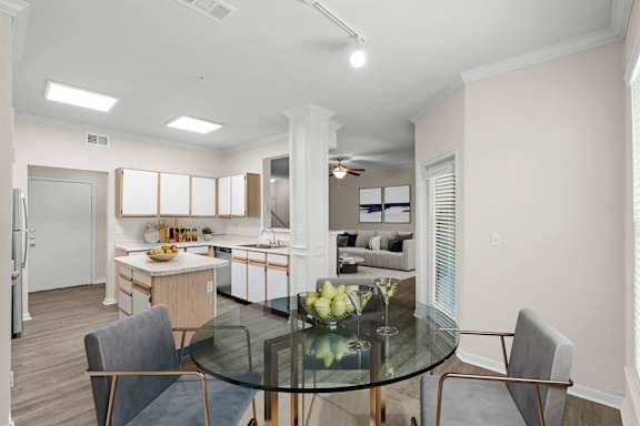 A dining area with track lighting and a large kitchen in the background.