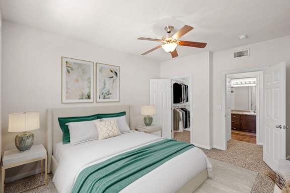 A bedroom with a ceiling fan, large walk in closet, and attached master bathroom.