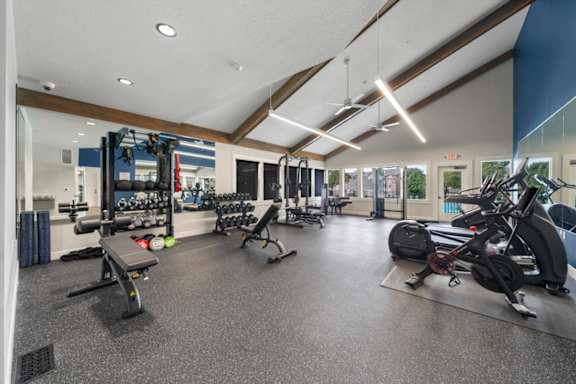 A gym with a variety of equipment including treadmills, weights, and exercise machines.
