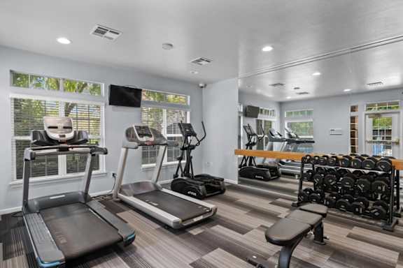 A gym with treadmills, elliptical machines, and dumbbells.at Crowne Chase Apartment Homes, Kansas, 66210