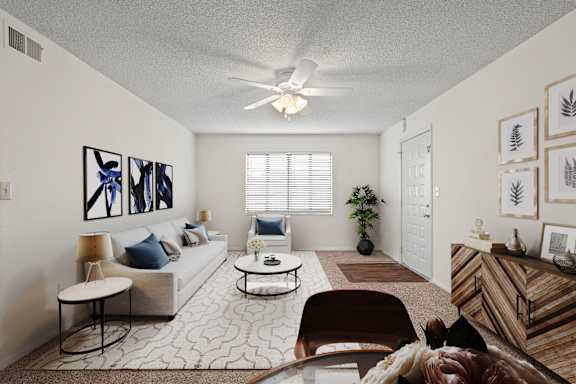A living room with a ceiling fan and a large window at Bristol Pointe Apartments in Olathe, Kansas.