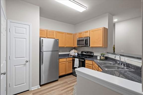 Kitchen with stainless steel appliances and wooden cabinets at Deer Creek Apartment Homes, Overland Park