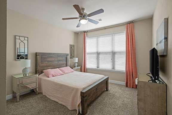 A bedroom with a bed, nightstand, and television.