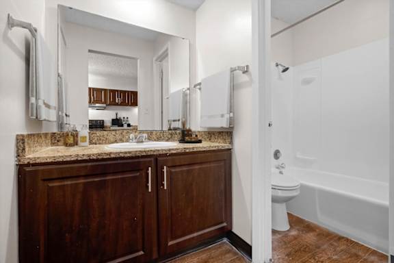 A bathroom with a white tub and wooden cabinets. at Malvern Hill Apartment Homes, 66103, KS