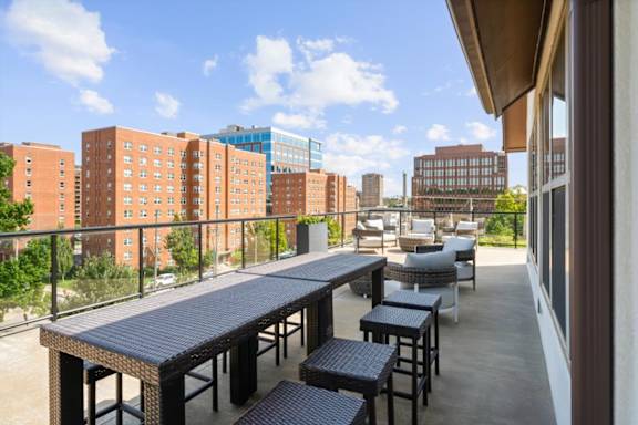 A balcony with a table and chairs overlooks a cityscape. at The Dorset, Kansas City, 64112