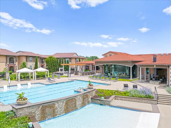 a large swimming pool with lounge chairs in front of a building