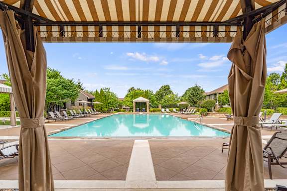 A pool area with a striped canopy over it.