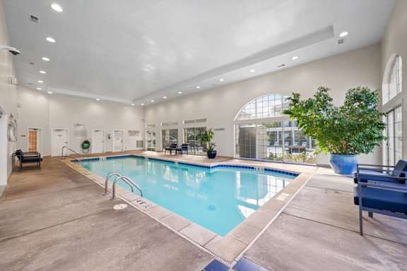 A large indoor swimming pool with a bench at The Claremont Apartment Homes, Kansas, 66210