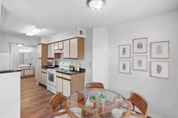 A kitchen and dining room with hardwood floors and white appliances.
