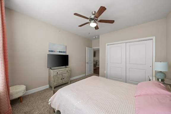 A bedroom with a bed, dresser, and television.