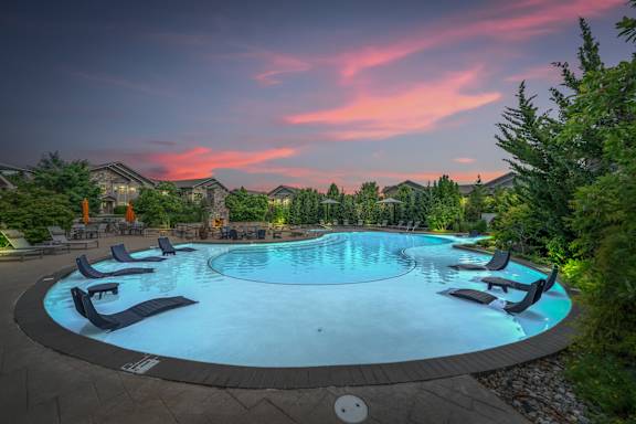 A round swimming pool surrounded by lounge chairs. at Stonepost Crossing Apartments, Overland Park, Kansas