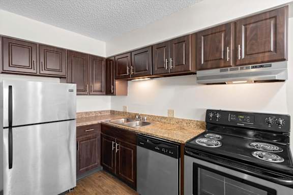 A kitchen with a stove, refrigerator, and cabinets. at Malvern Hill Apartment Homes, Kansas
