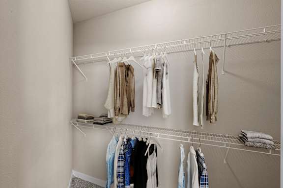 A large walk-in bedroom closet with built-in wire racks.