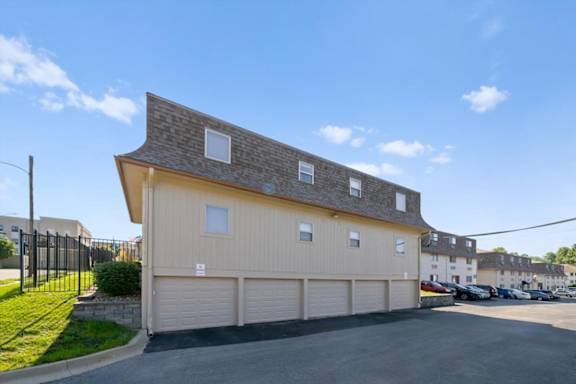 A two-story building with a garage door and a driveway in front. at Malvern Hill Apartment Homes, Kansas
