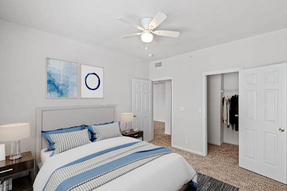 A bedroom with a ceiling fan and large walk in closet.