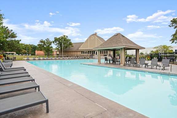A large swimming pool with sun loungers and a pavilion in the background.