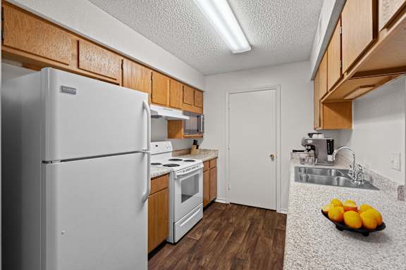A kitchen with a white refrigerator and wooden cabinets.