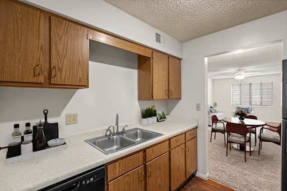 A kitchen with wooden cabinets, white countertops and a black dishwasher in an apartment at Bristol Pointe in Olathe, Kansas.