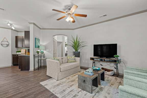 A living room with a beige couch, a wooden coffee table, and a television on a stand.