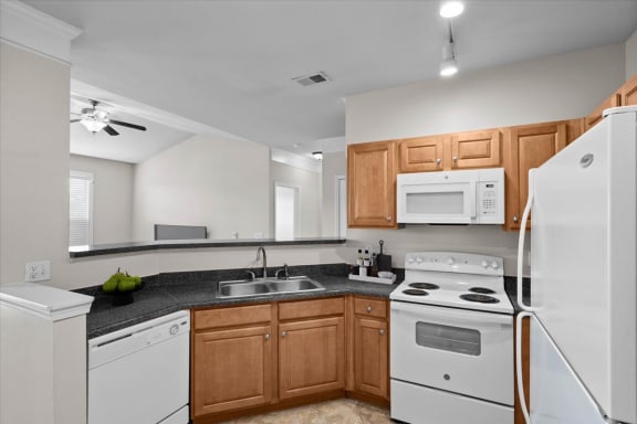a kitchen with white appliances and wooden cabinets at Stonepost Ranch, Overland Park, KS