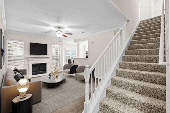 A living room with a staircase and a ceiling fan.