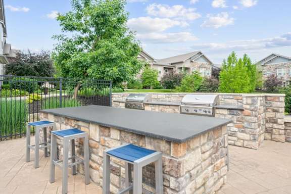 A barbecue grill is on a stone patio. at Stonepost Crossing Apartments, Kansas, 66213